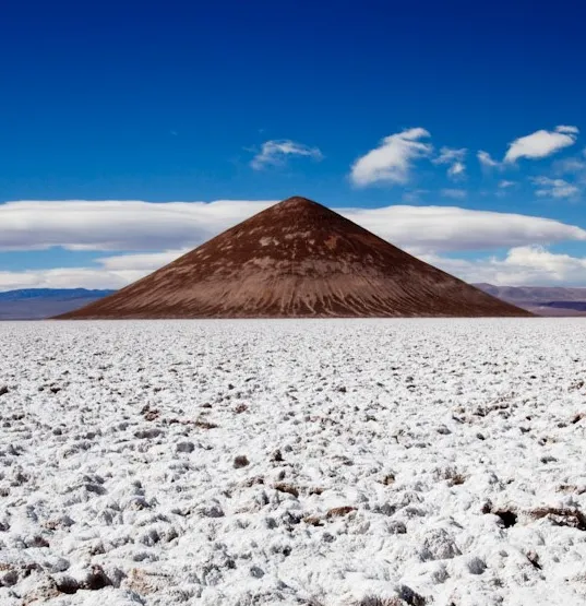 Cerro en forma de cono en medio de un salar blanco
