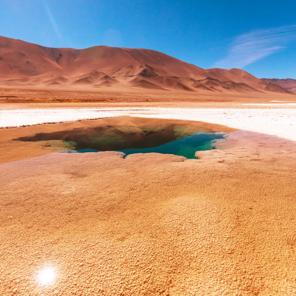 Pequeño espejo de agua turquesa entre suelos ocres y dorados