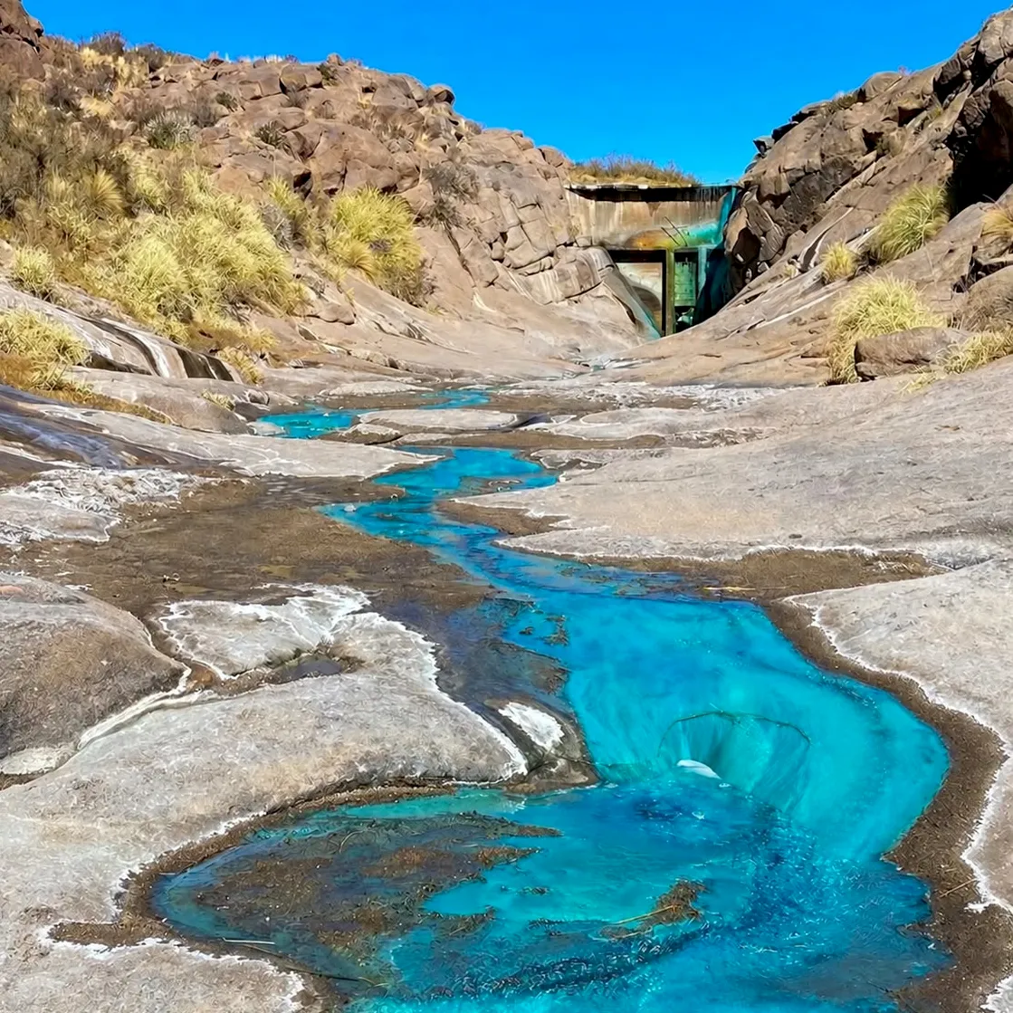 Agua turquesa que corre entre rocas en una quebrada