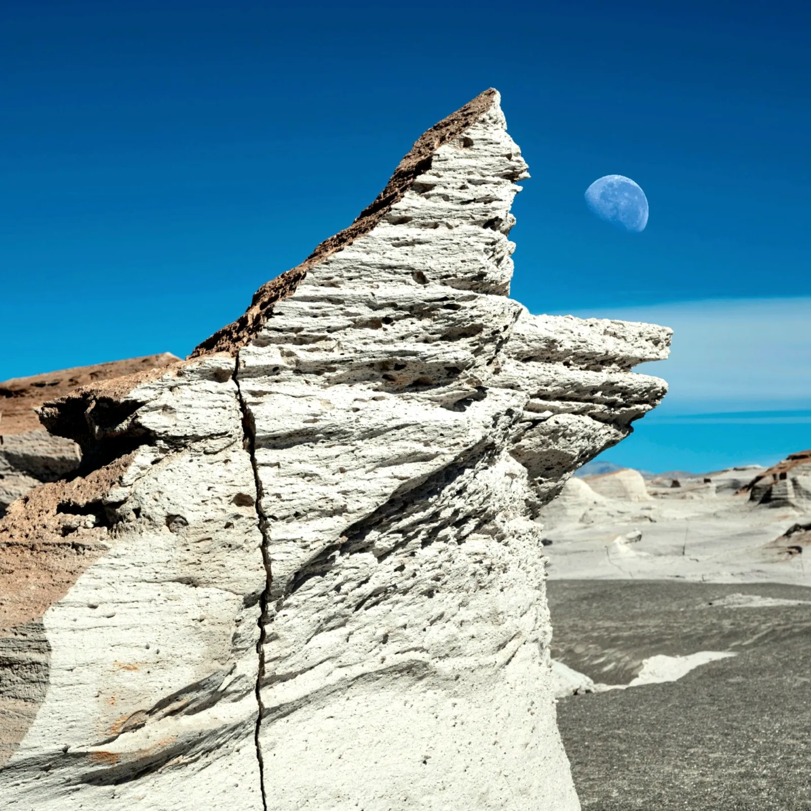Formación blanca de piedra pómez con la luna de fondo