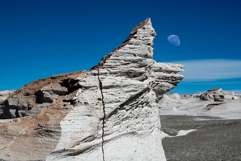 Formación blanca de piedra pómez con la luna en el cielo azul